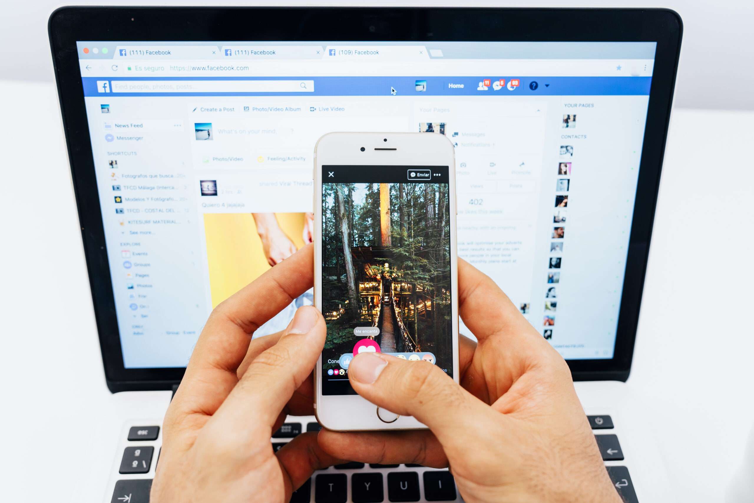 "Person engaged in a Facebook marketing campaign, simultaneously using the app on a mobile phone and a laptop."